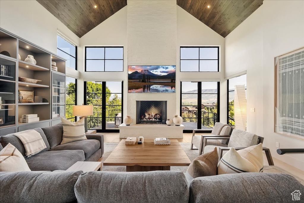 Living area with high vaulted ceiling, wooden ceiling, a large fireplace, and recessed lighting