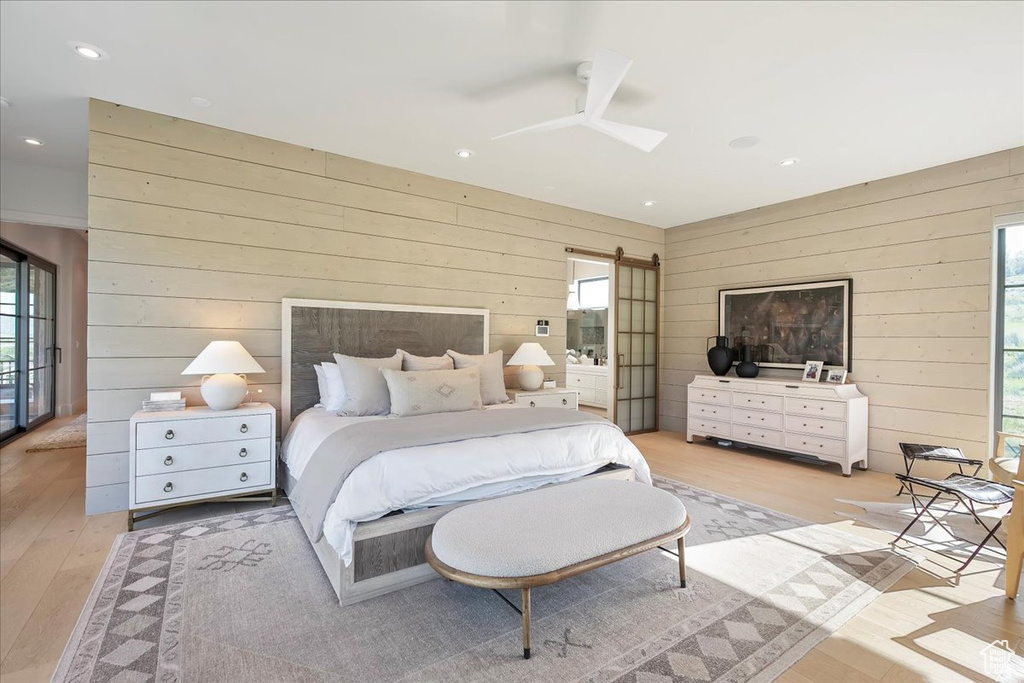 Bedroom with wooden walls, multiple windows, light wood-type flooring, recessed lighting, and ceiling fan