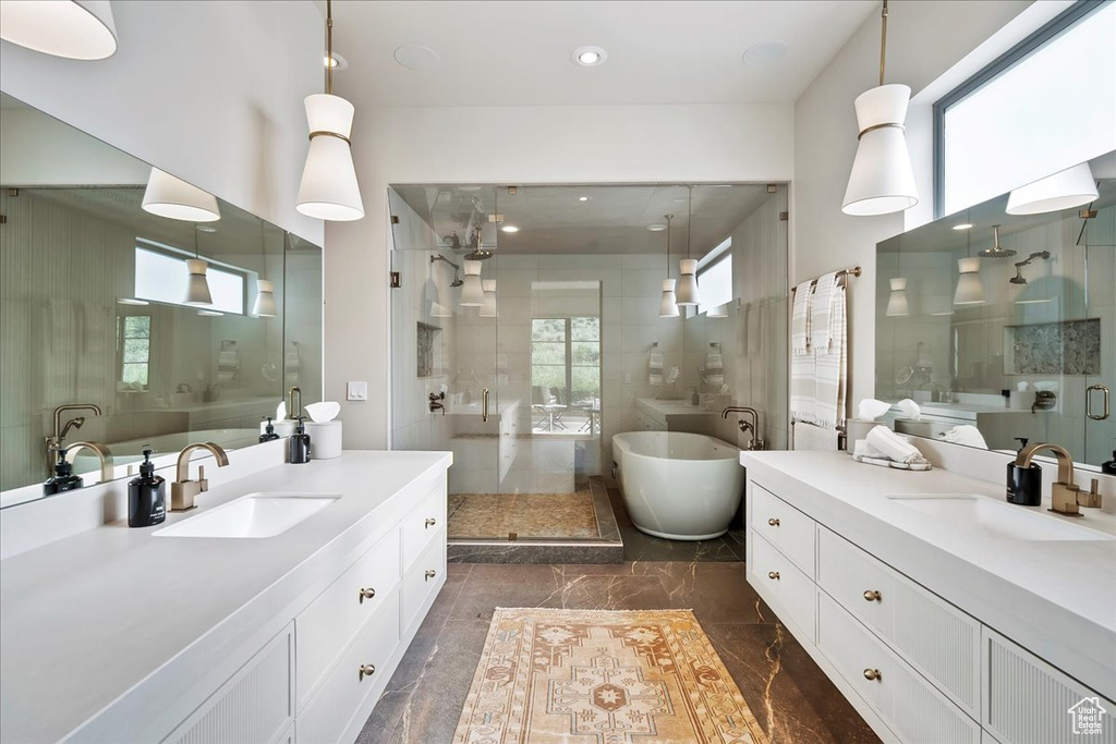 Full bathroom featuring a shower stall, two vanities, a freestanding bath, marble tiled flooring, and recessed lighting