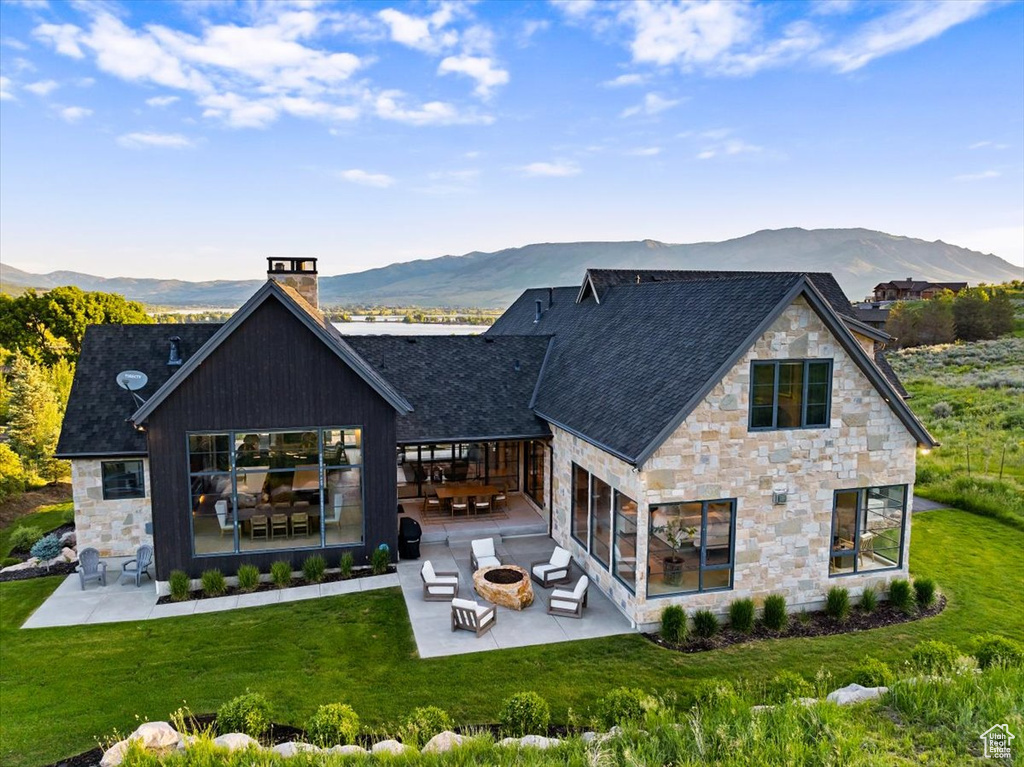Rear view of house featuring an outdoor fire pit, a patio area, and stone siding