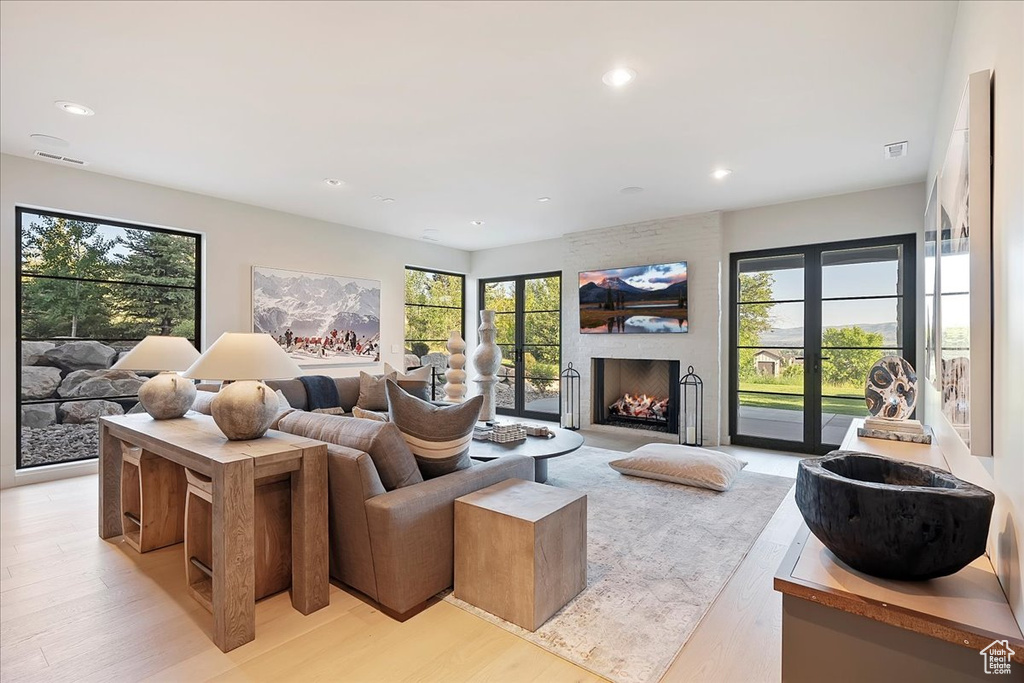 Living room with light wood-style flooring, a large fireplace, and recessed lighting