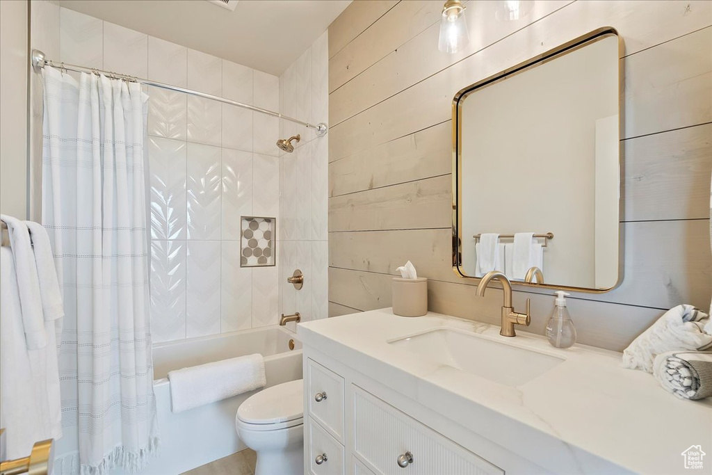 Full bath with shower / bathtub combination with curtain, vanity, and wooden walls