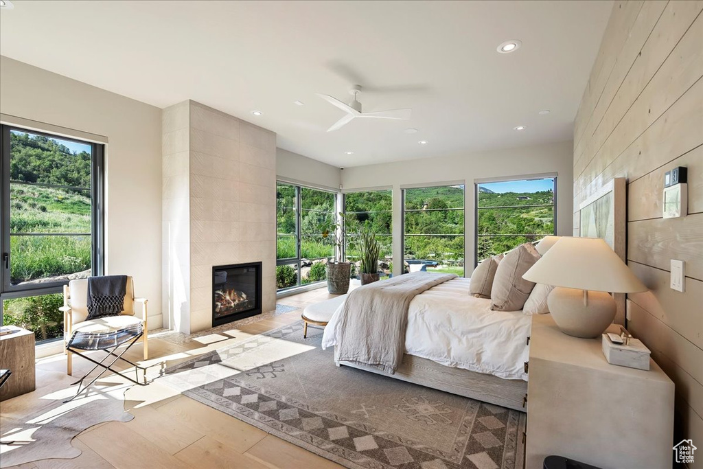 Bedroom with wood finished floors, a tile fireplace, recessed lighting, and ceiling fan