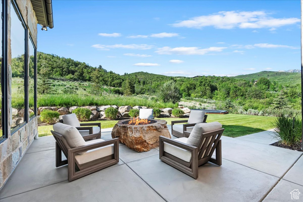 View of patio / terrace featuring an outdoor fire pit, a view of trees, and a mountain view