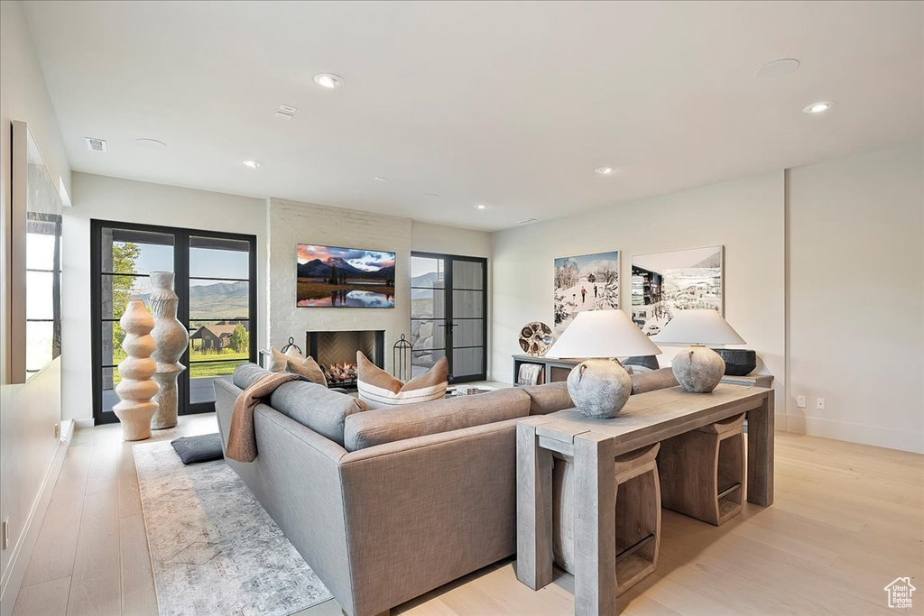 Living room featuring light wood-type flooring, recessed lighting, and a large fireplace