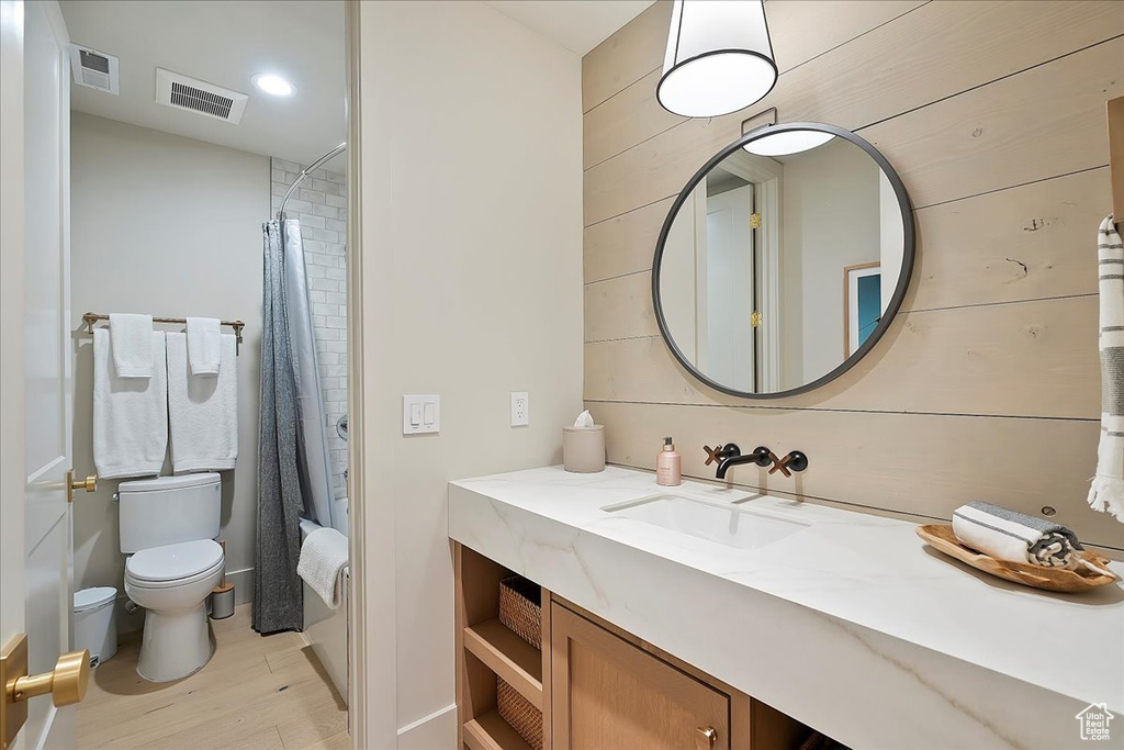 Full bath with wood finished floors, vanity, and shower / bath combo with shower curtain