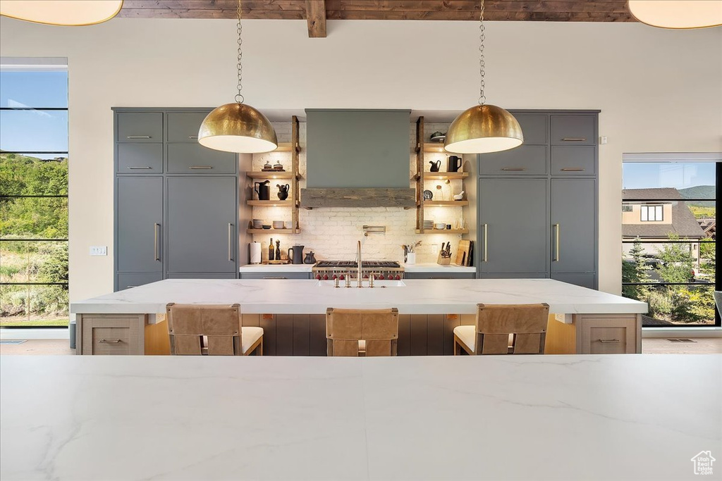 Bar area with tasteful backsplash, range hood, beam ceiling, and decorative light fixtures