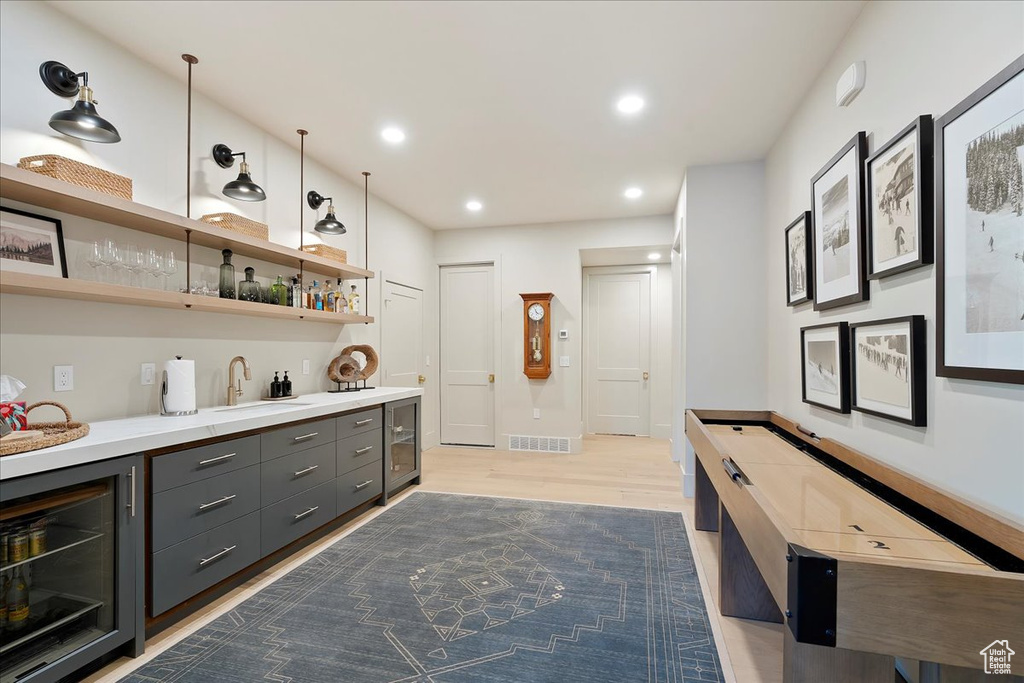 Indoor wet bar with wine cooler, light wood finished floors, and recessed lighting