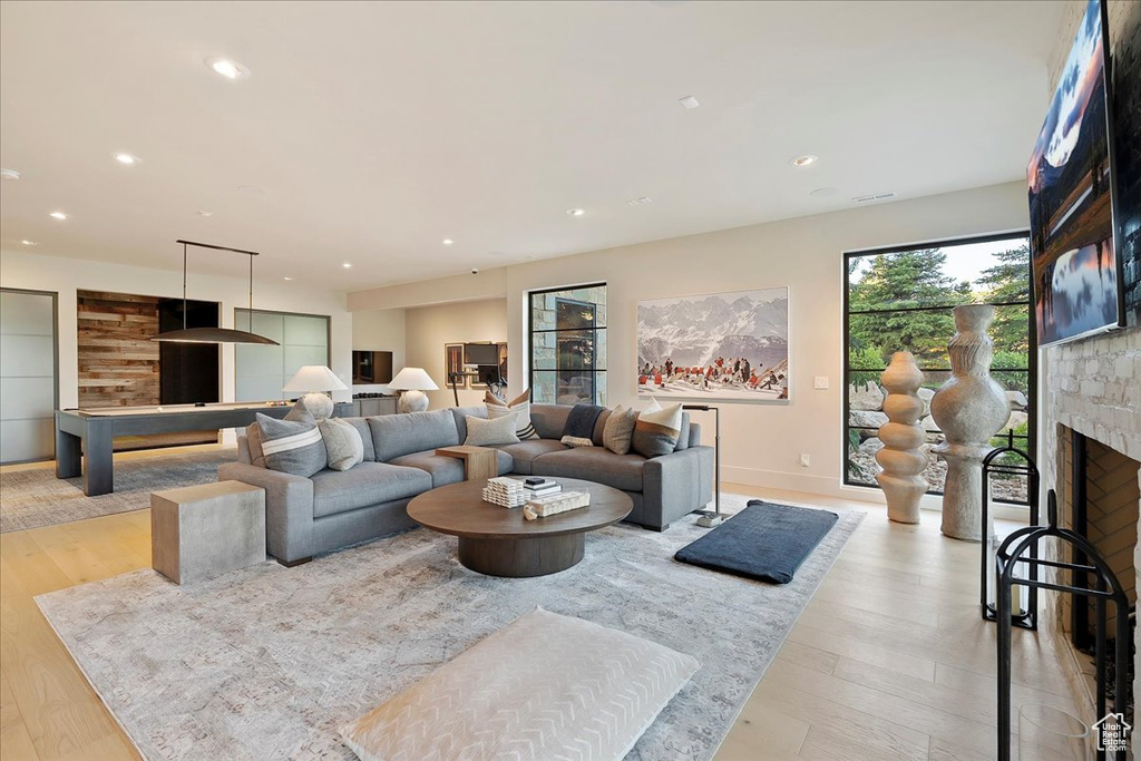 Living area with a large fireplace, light wood-style flooring, and recessed lighting