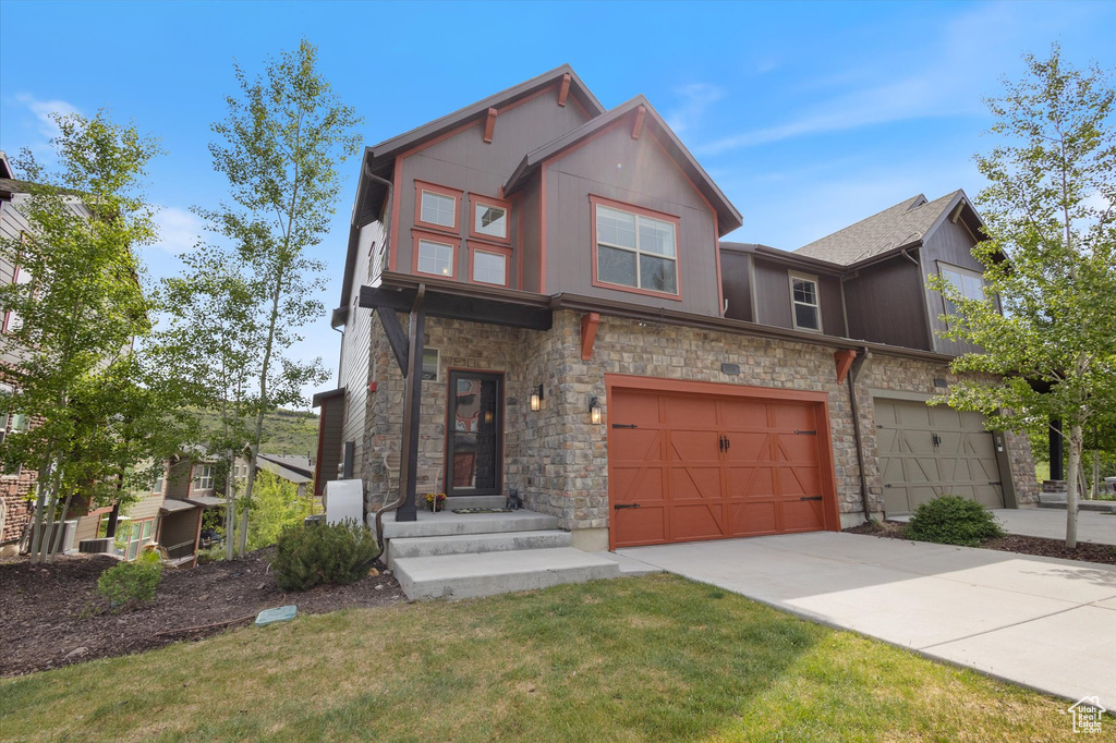 View of front of home featuring stone siding, driveway, a garage, and a front yard