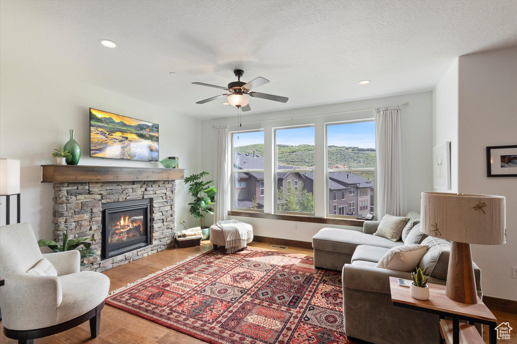 Living area with ceiling fan, a fireplace, wood finished floors, and recessed lighting