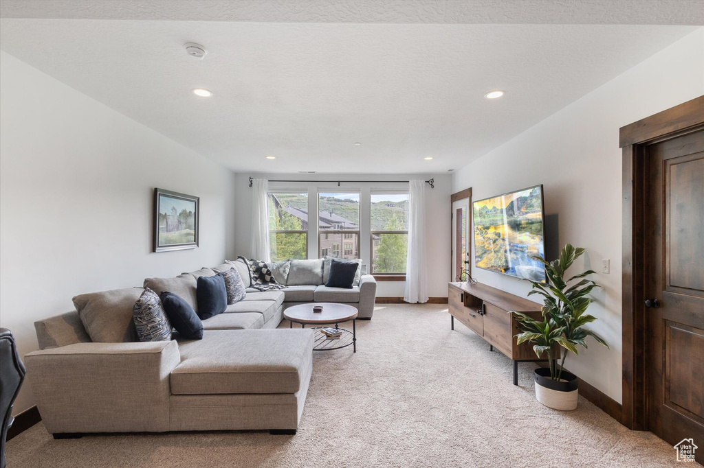 Living area with light carpet and recessed lighting