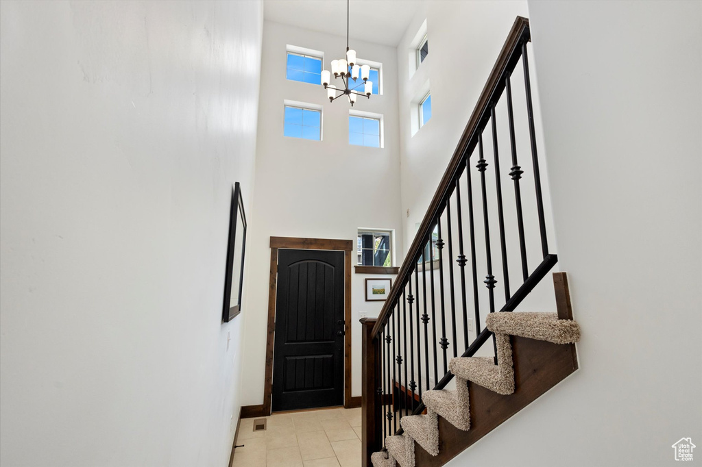 Foyer entrance with a chandelier, stairs, a high ceiling, and light tile patterned floors