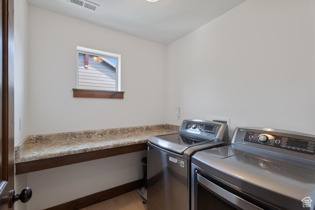 Laundry room featuring washing machine and dryer and light tile patterned floors