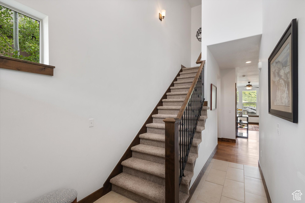 Stairs featuring tile patterned floors, recessed lighting, and a ceiling fan