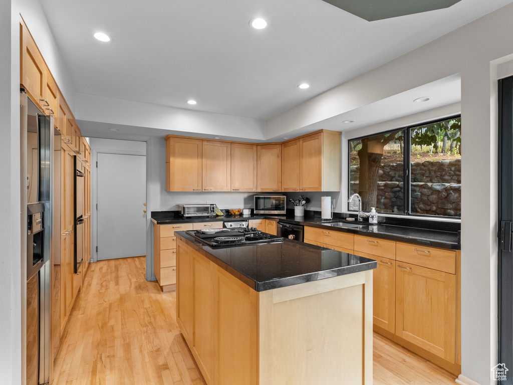 Kitchen featuring cooktop, black dishwasher, light brown cabinetry, light wood-type flooring, and recessed lighting