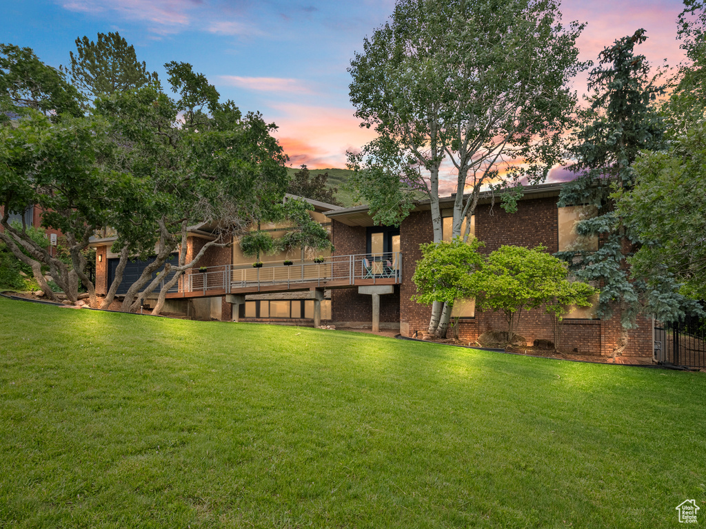 Rear view of house featuring a lawn, brick siding, and a wooden deck