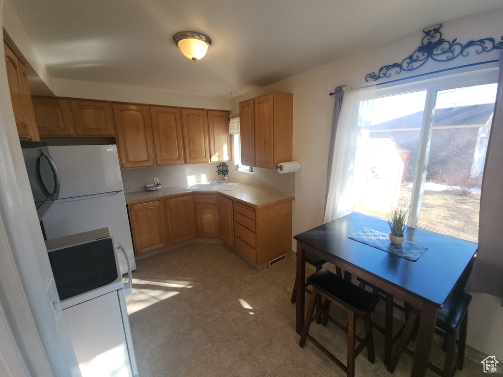 Kitchen with plenty of natural light, freestanding refrigerator, and light floors