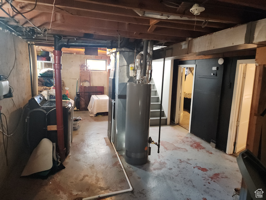 Unfinished basement with water heater, washer and dryer, and stairs
