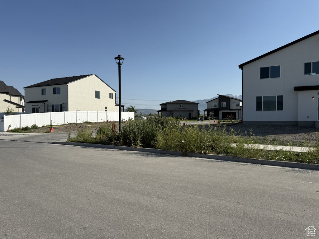 View of asphalt street featuring curbs, street lights, and a residential view