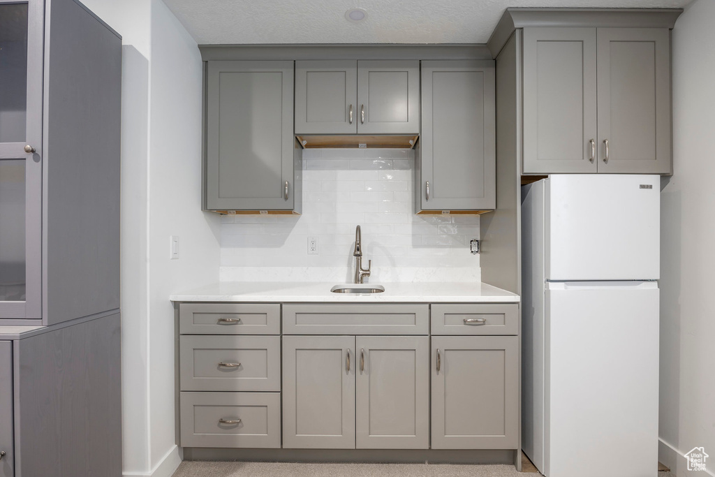 Kitchen featuring freestanding refrigerator, gray cabinets, light countertops, and backsplash
