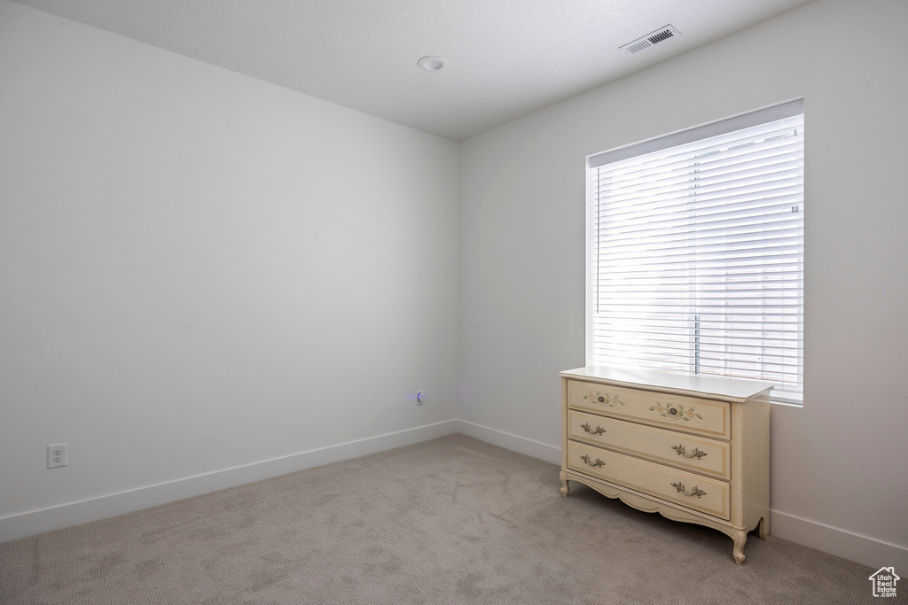 Spare room featuring light colored carpet and baseboards