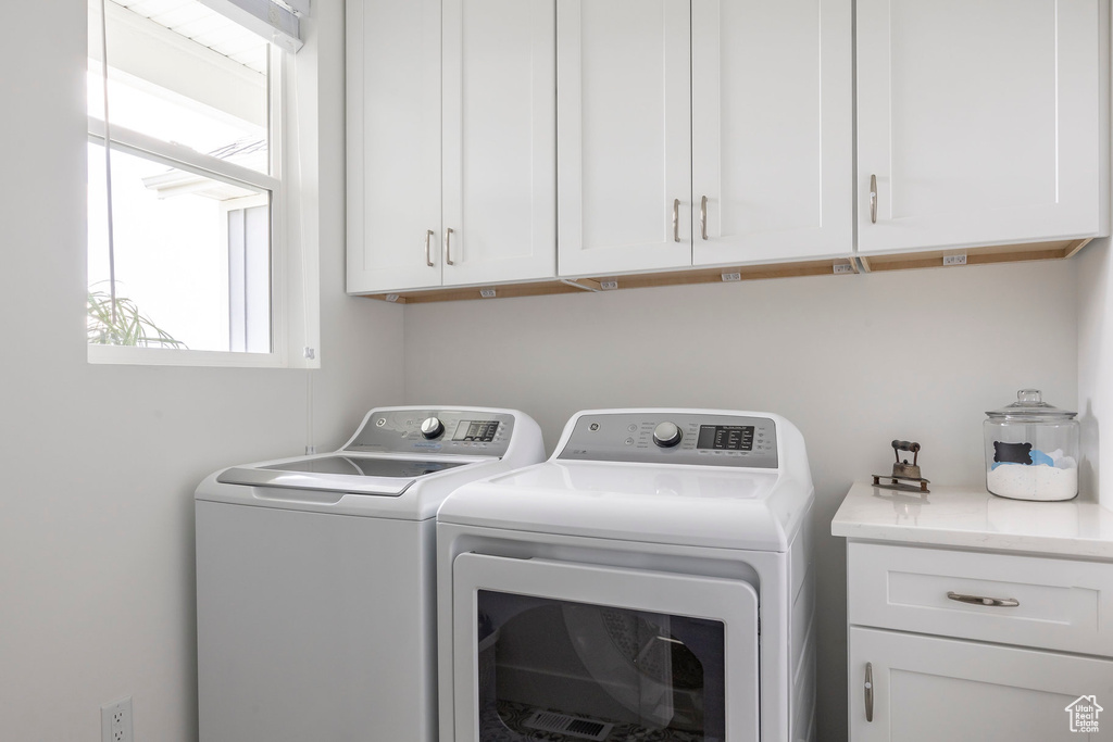 Laundry area featuring separate washer and dryer and cabinet space