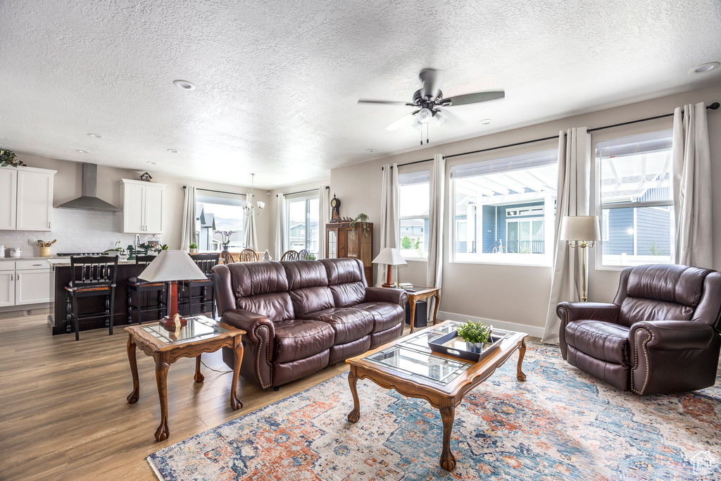 Living area with a textured ceiling, wood finished floors, and a ceiling fan