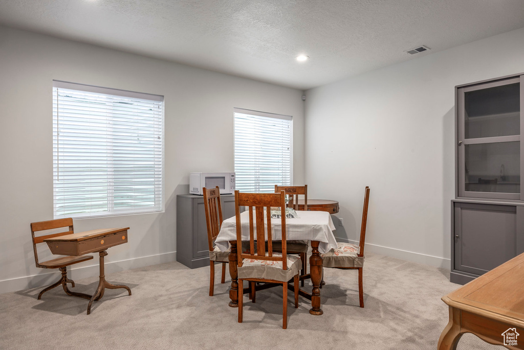 Dining room featuring light colored carpet, a textured ceiling, and recessed lighting