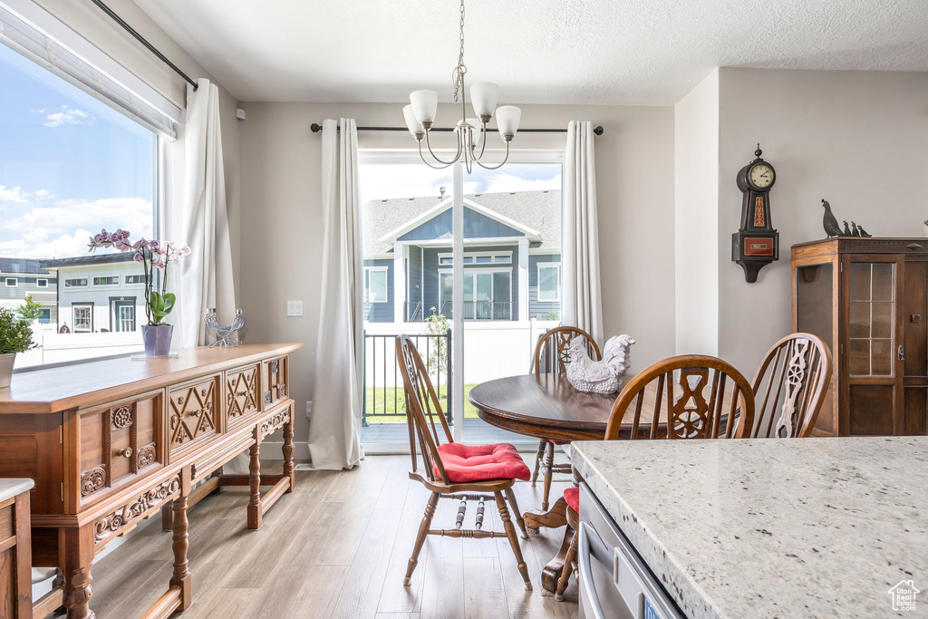 Dining space with a chandelier, light wood-style floors, plenty of natural light, and a textured ceiling