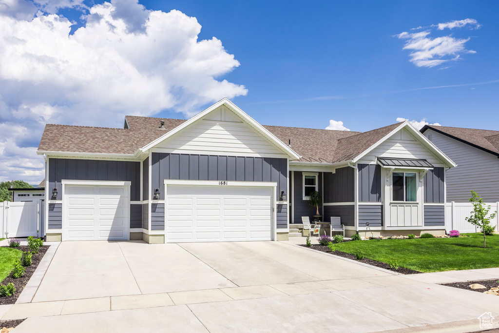 Single story home featuring board and batten siding, an attached garage, driveway, and roof with shingles