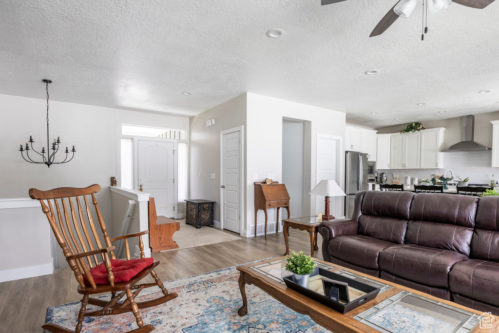 Living area featuring wood finished floors, a textured ceiling, a ceiling fan, and a chandelier