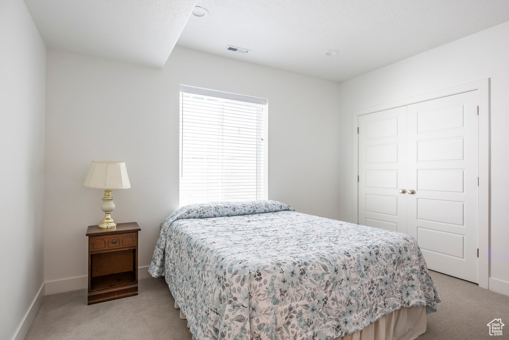 Bedroom with light colored carpet and a closet