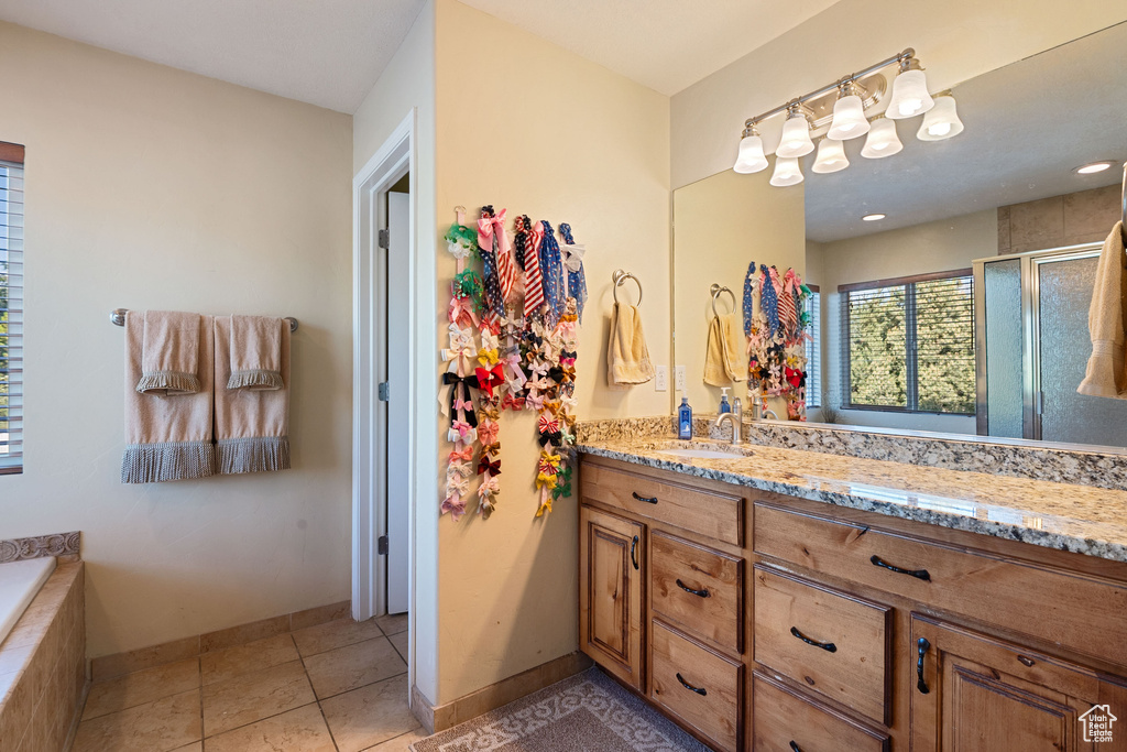 Bathroom with a stall shower, vanity, tile patterned floors, and tiled bath