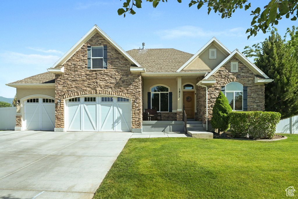 View of front of property with stucco siding, stone siding, a garage, concrete driveway, and roof with shingles