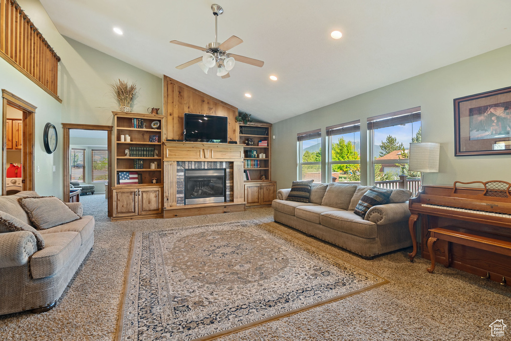 Carpeted living area featuring a ceiling fan, recessed lighting, a glass covered fireplace, and high vaulted ceiling