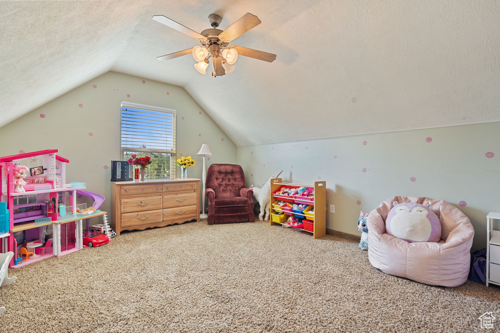 Recreation room with carpet floors, lofted ceiling, a ceiling fan, and a textured ceiling