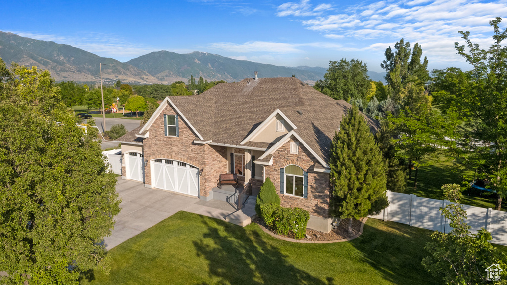 View of front of property with stone siding, concrete driveway, a garage, and a mountain view