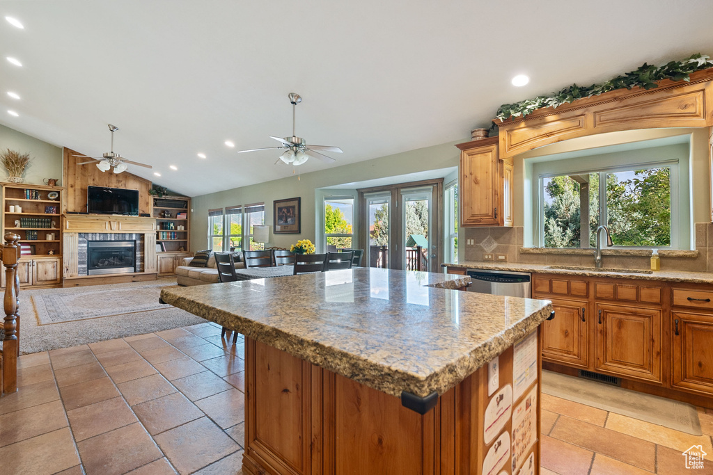 Kitchen with ceiling fan, a glass covered fireplace, tasteful backsplash, dishwasher, and vaulted ceiling
