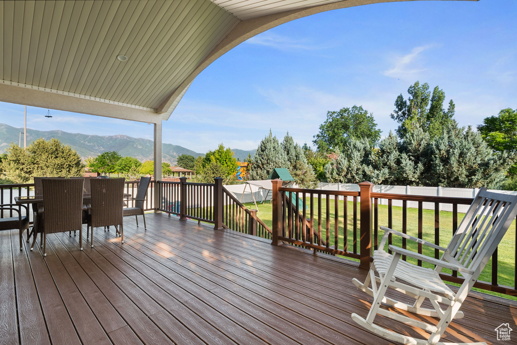 Deck with a mountain view, a fenced backyard, and outdoor dining area