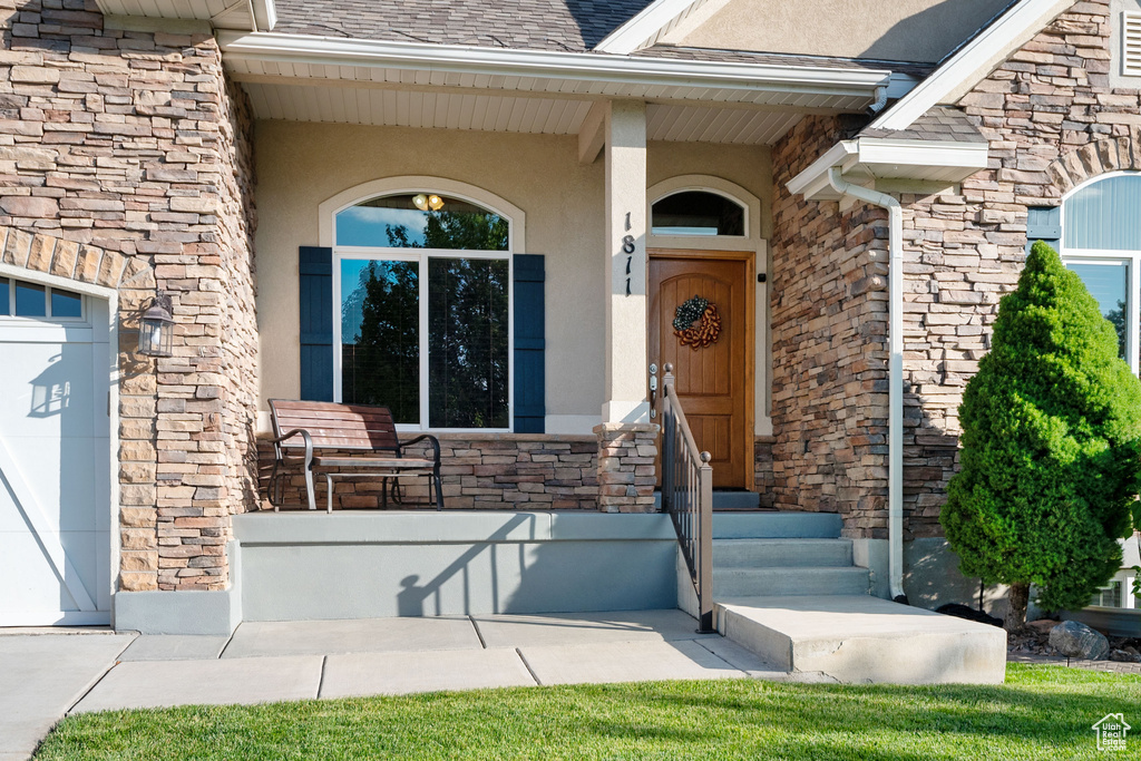View of exterior entry featuring stone siding and stucco siding