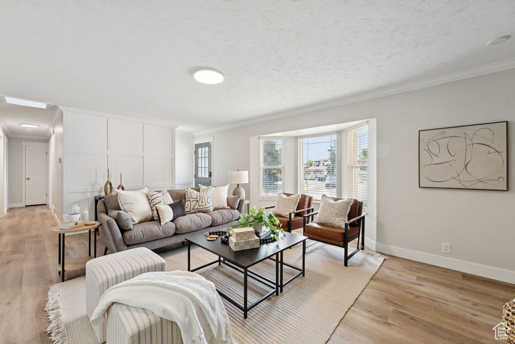 Living area with ornamental molding and light wood-style floors