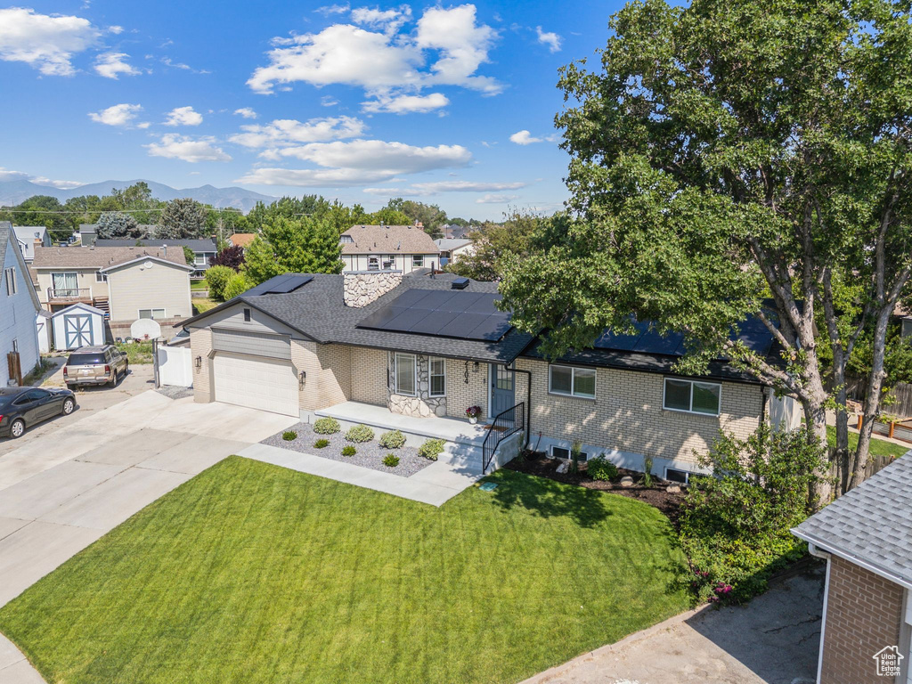 Single story home featuring a front lawn, a residential view, concrete driveway, brick siding, and solar panels