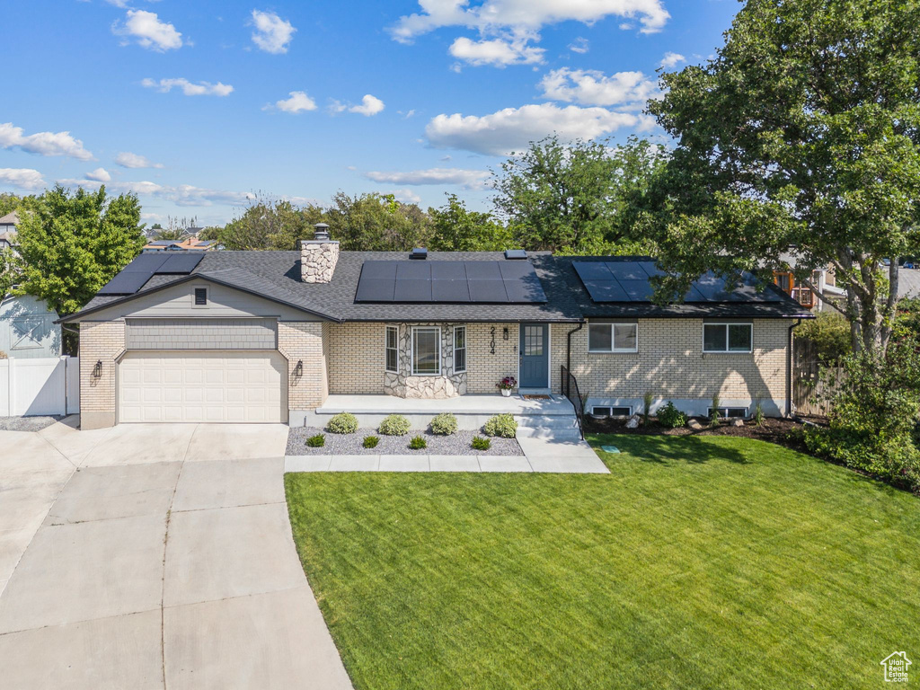 Ranch-style house featuring driveway, a garage, brick siding, and solar panels