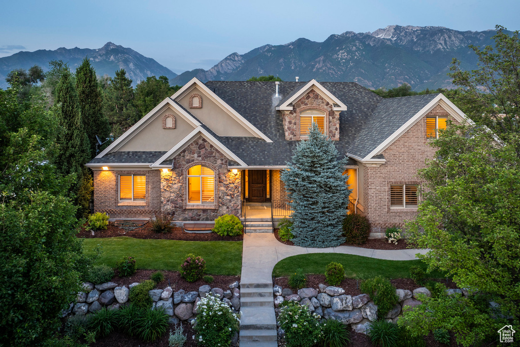 View of front of house featuring stone siding, stucco siding, a mountain view, and a front yard