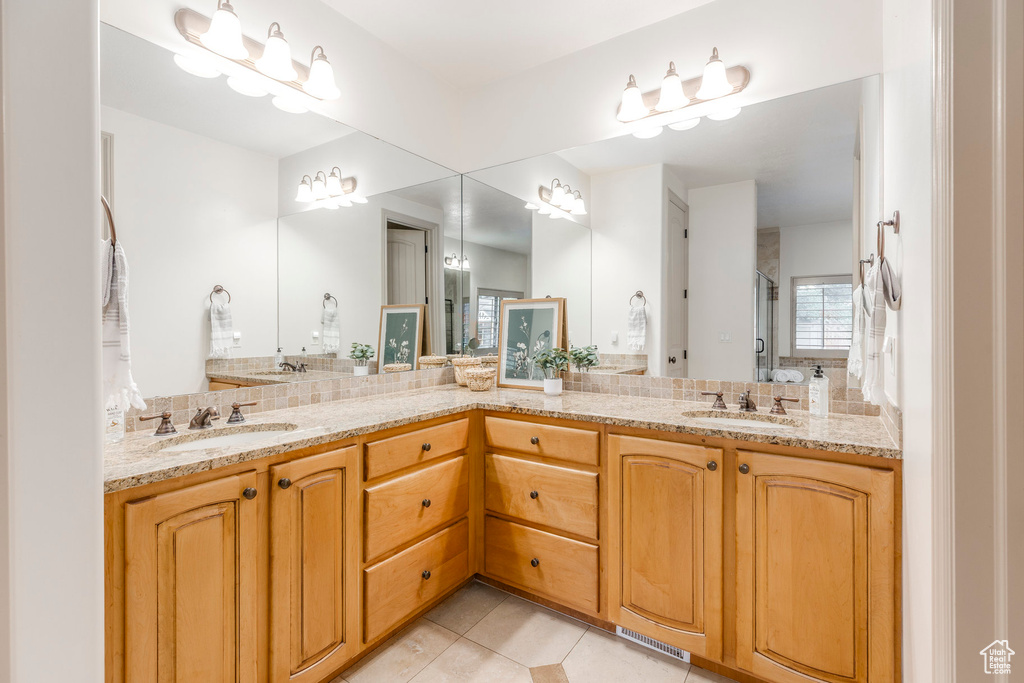 Bathroom with double vanity, tile patterned flooring, and decorative backsplash