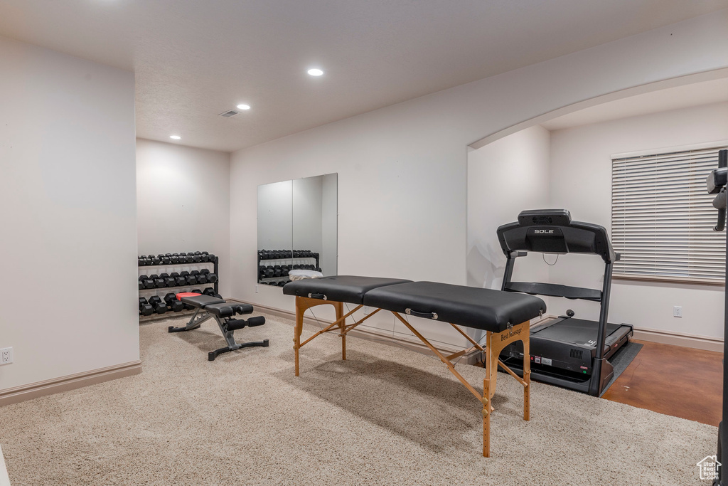 Exercise room featuring arched walkways, recessed lighting, and carpet flooring