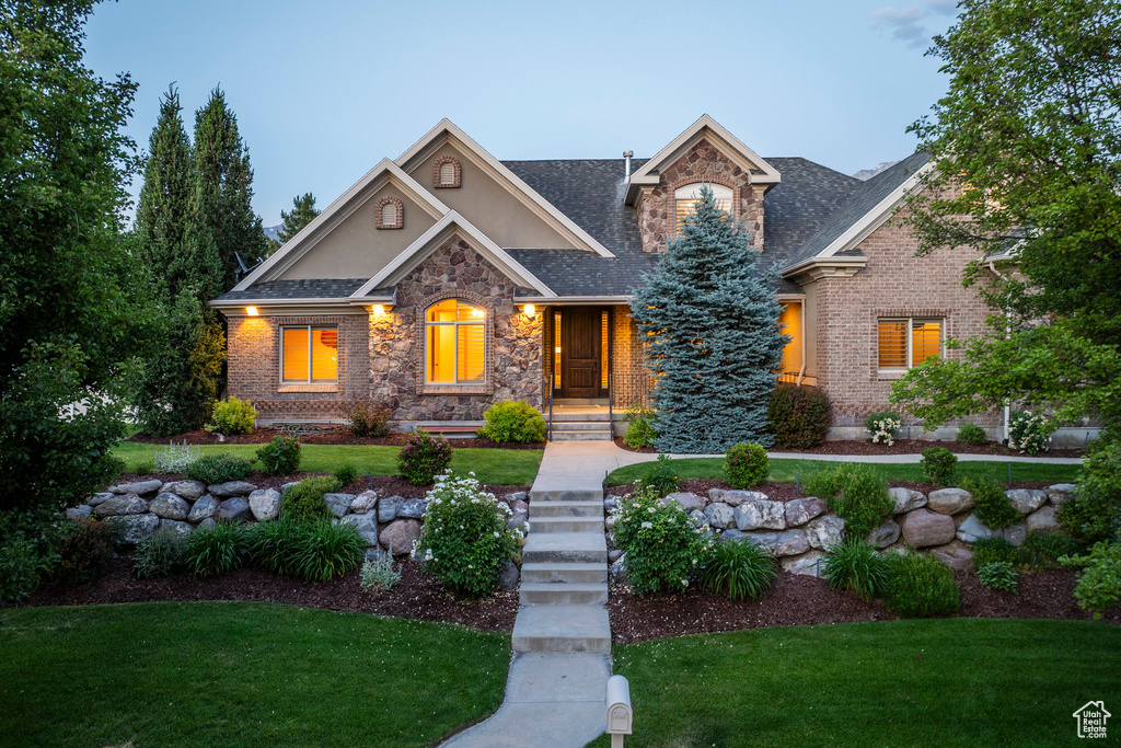 Craftsman house featuring stone siding, stucco siding, and a front lawn