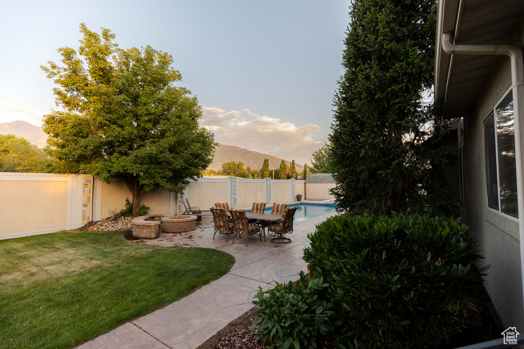 Fenced backyard featuring a mountain view, an outdoor fire pit, and a patio area