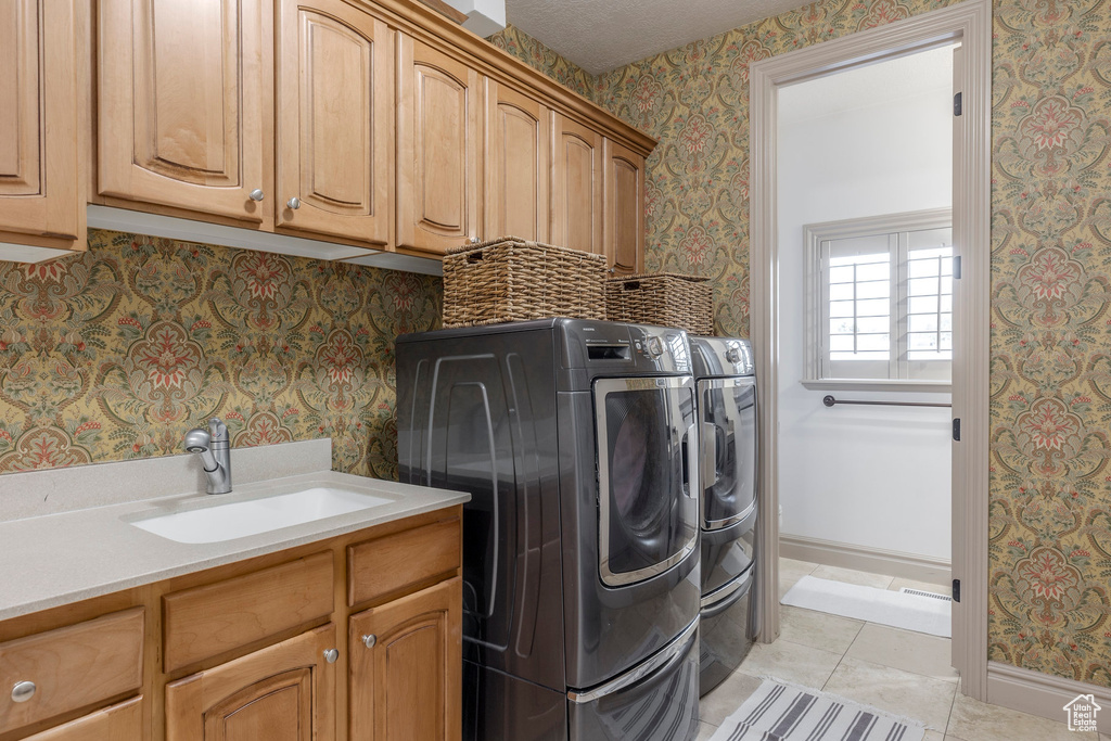 Laundry room featuring cabinet space, wallpapered walls, separate washer and dryer, and light tile patterned flooring